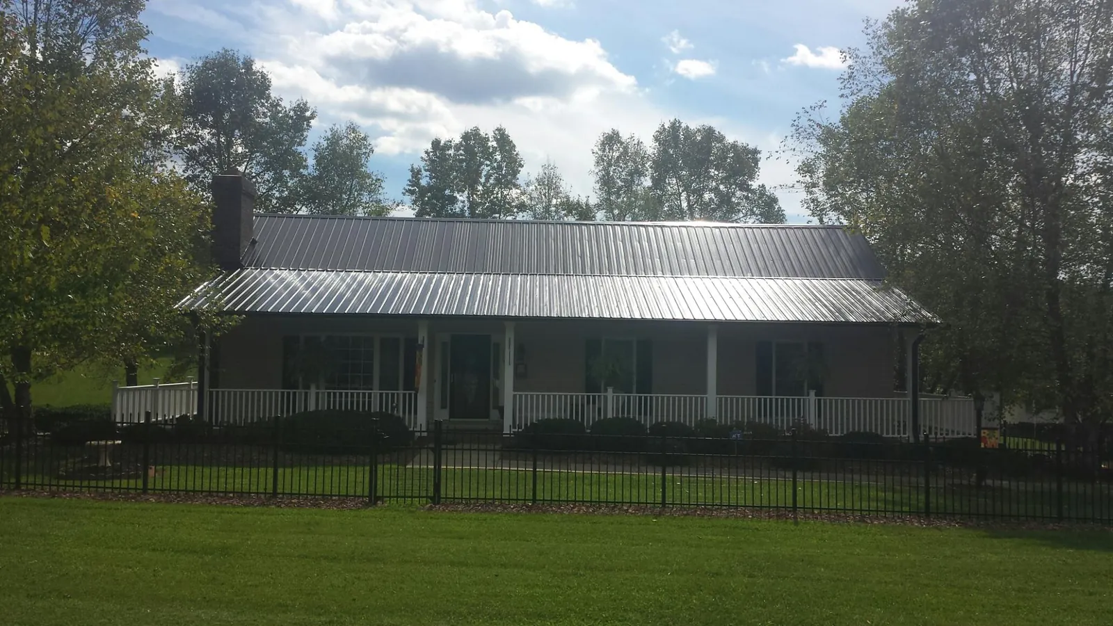 Gray metal roof on a brick ranch with a full width front porch — Gutter Guard Installation work by our crew in Harrisburg